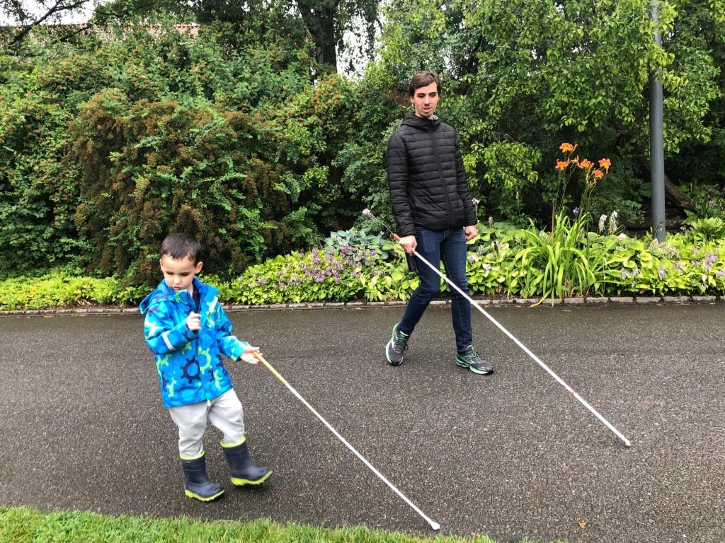 Et barn og en voksen går med lange mobilitetsstokker