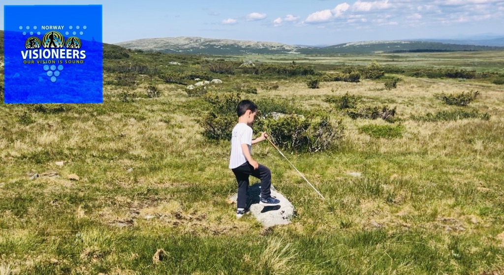 Visioneers-student på fire år som går med stokk på fjelltur