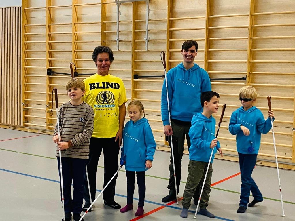 Kid Visioneers samling med Daniel og Thomas som står sammen med fire barn i en gymsal.